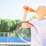 A tennis player drinks a sports drink