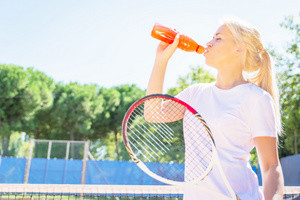 A tennis player drinks a sports drink