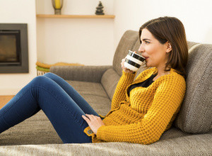 A woman at home drinking a cup of green tea.